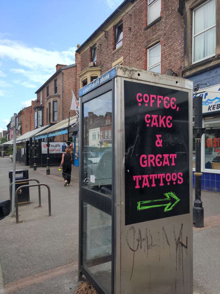 Phone box advertising the Holy Mackerel Tattoo Cafe in New Brighton